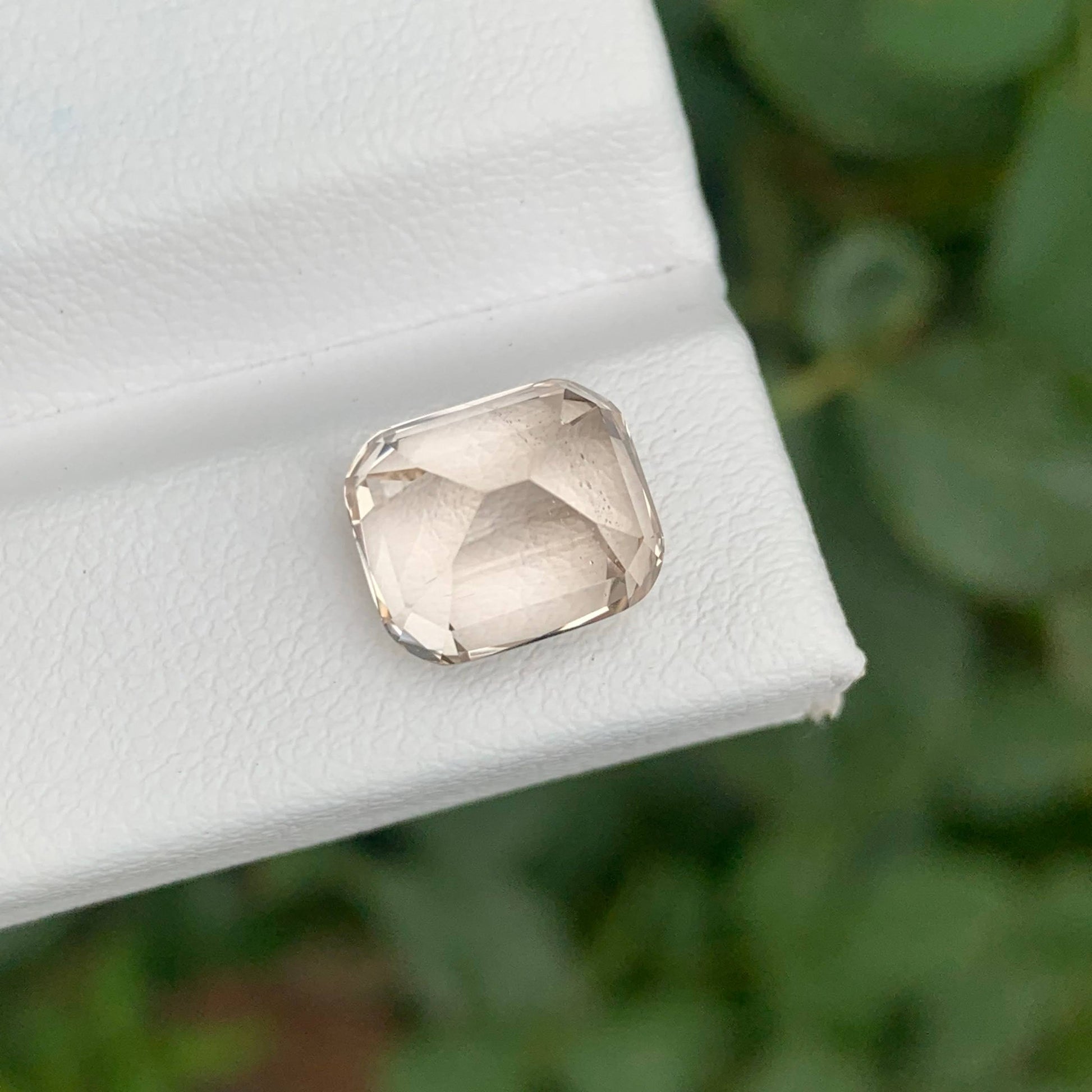 Faceted gemstone on a white box with a blurred green background