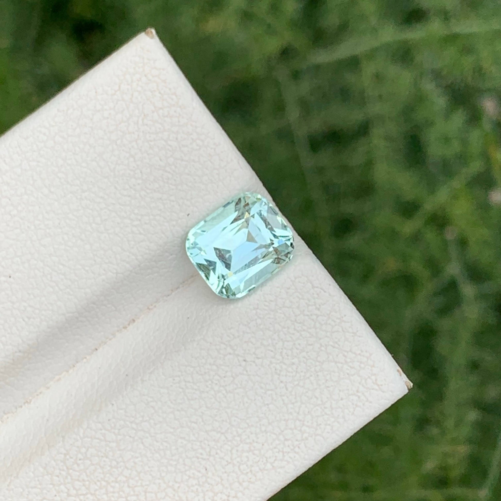 Green gemstone on a white cloth with a green leafy background