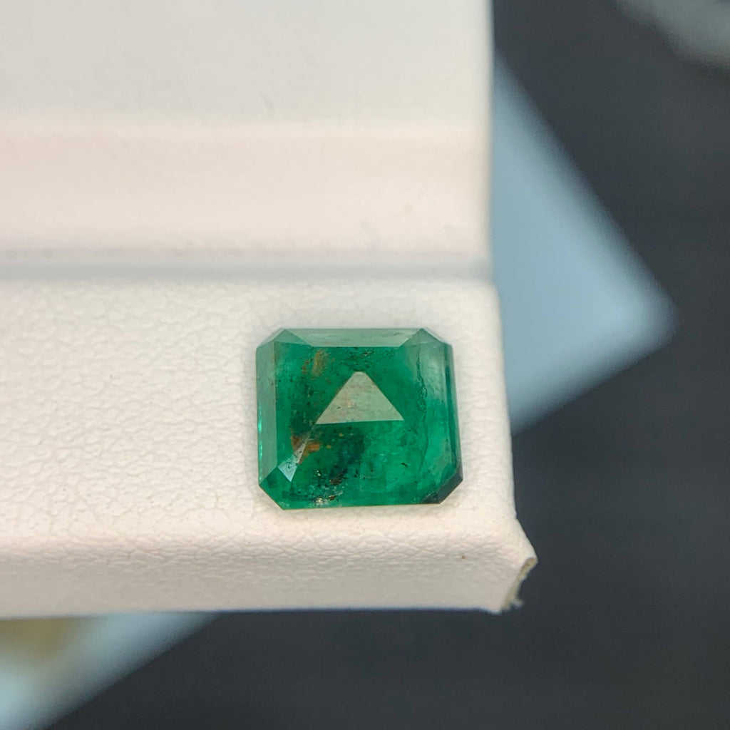 Emerald gemstone on a white stand with a blurred background
