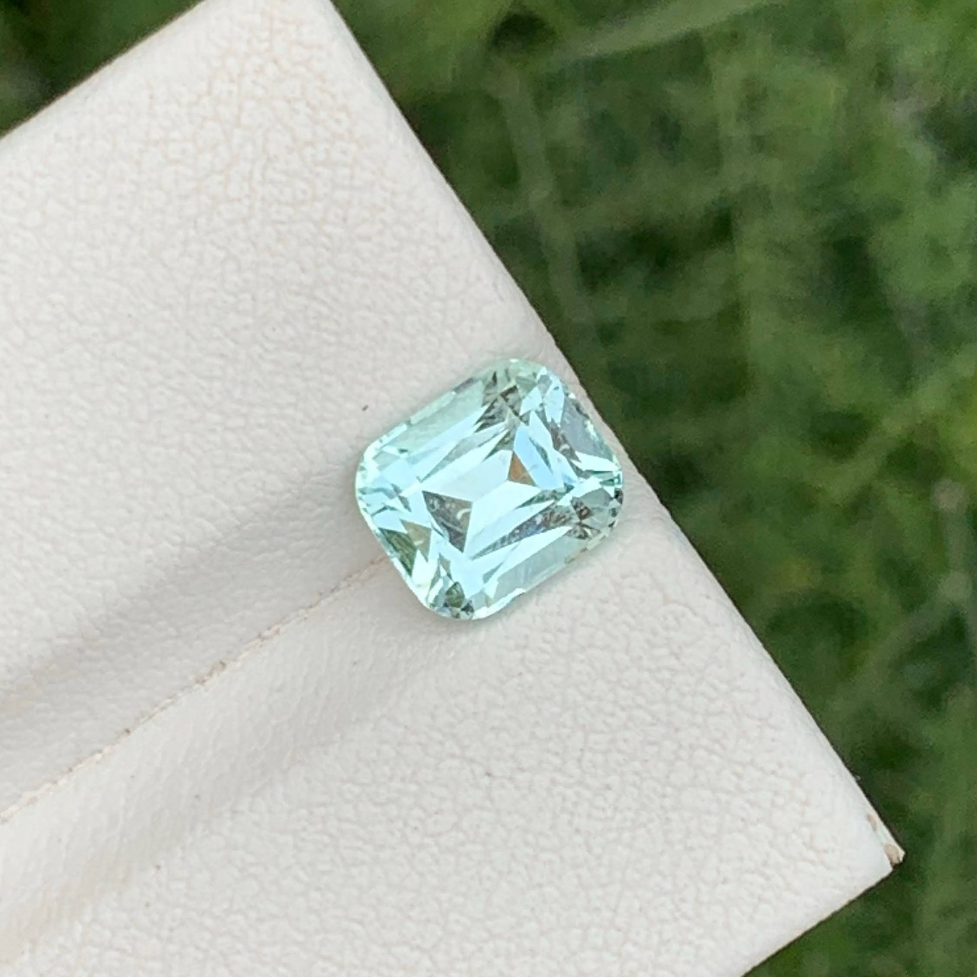 Green gemstone on a white cloth with a natural background