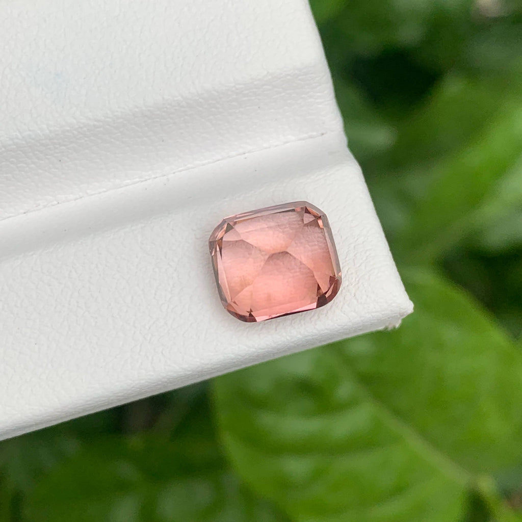4.35 Carats Pink Tourmaline Stone Cushion Cut Natural Afghan Gemstone on a white stand with green leaves in the background