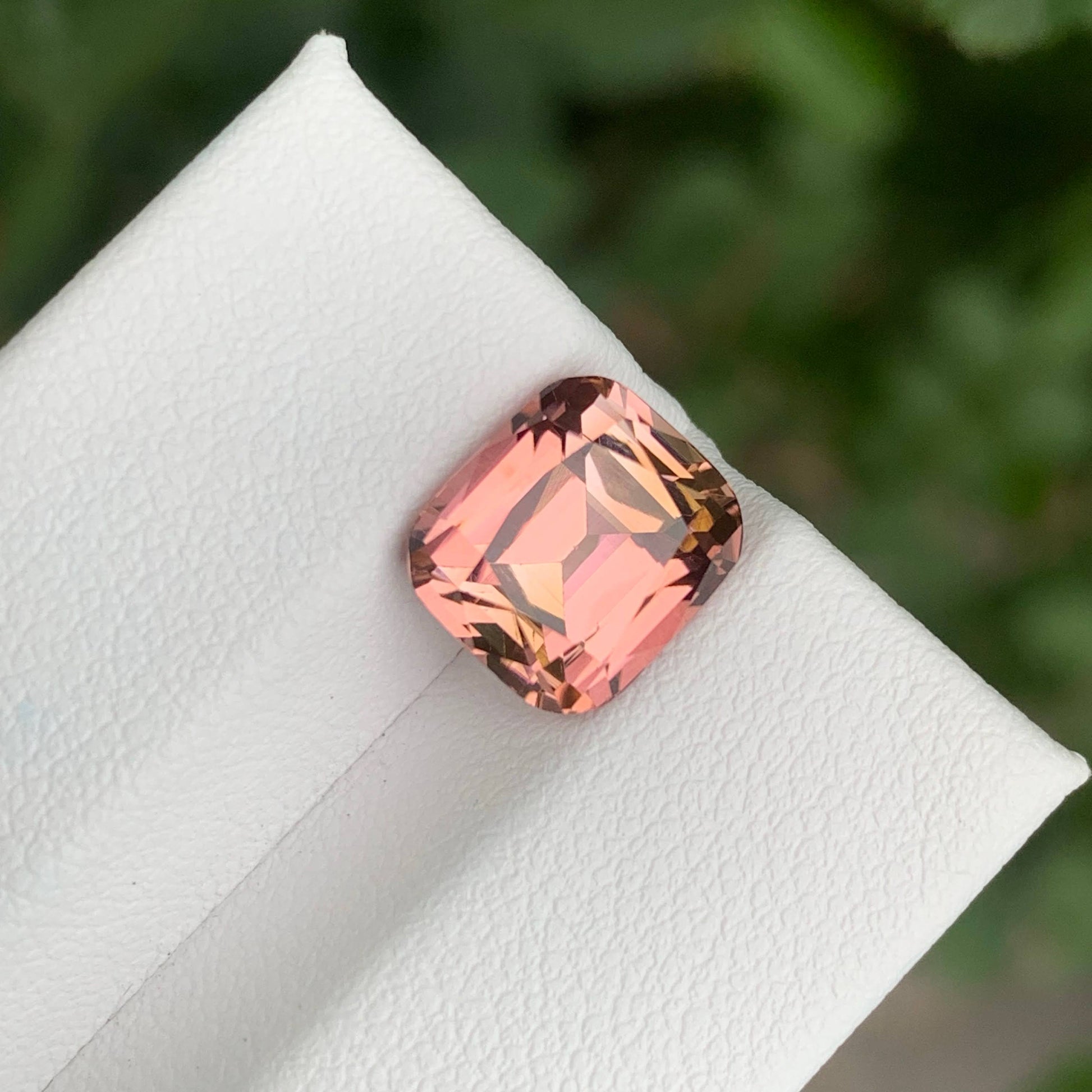 4.35 Carats Pink Tourmaline Stone Cushion Cut Natural Afghan Gemstone on a white stand with green leaves in the background