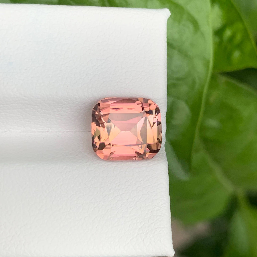 4.35 Carats Pink Tourmaline Stone Cushion Cut Natural Afghan Gemstone on a white stand with green leaves in the background