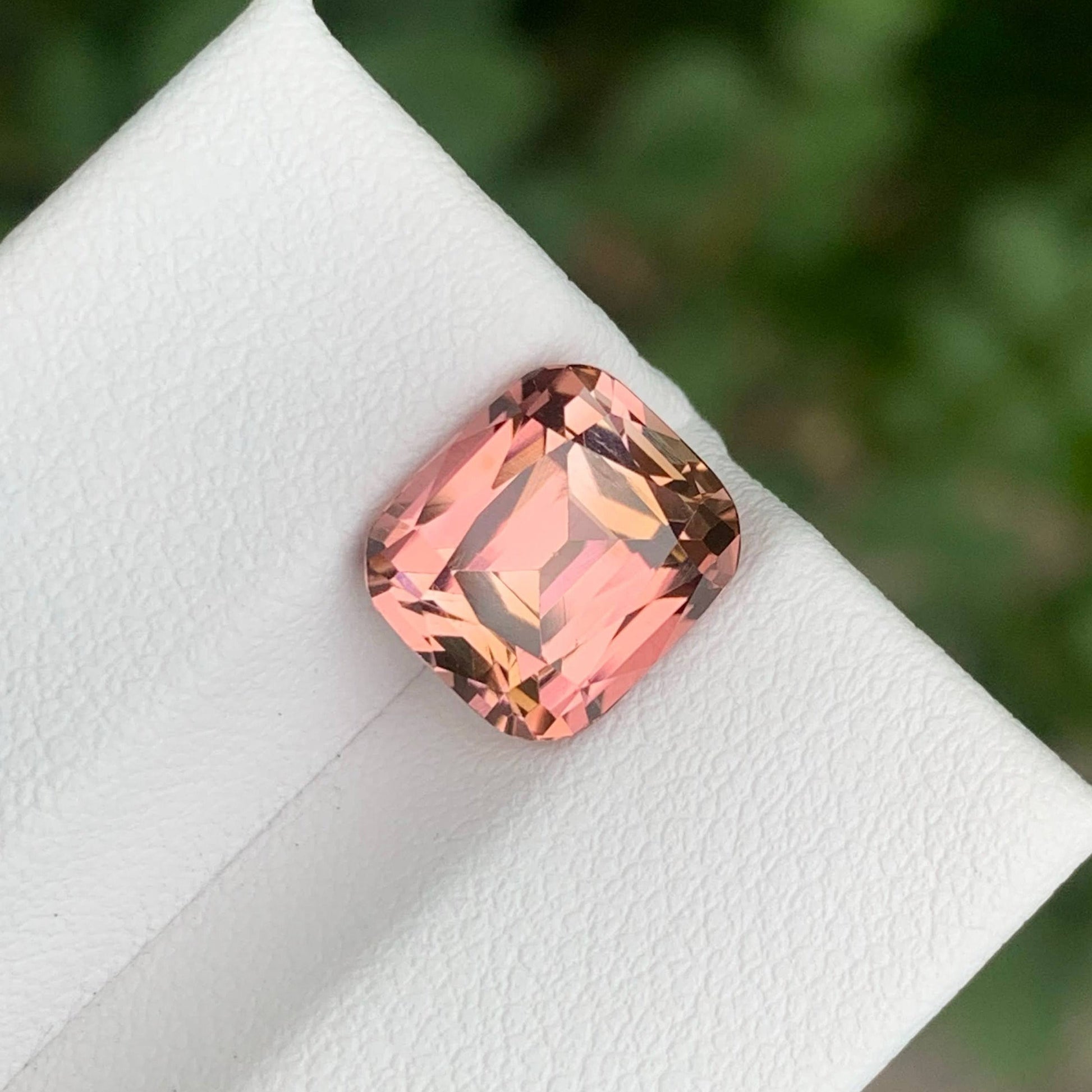 4.35 Carats Pink Tourmaline Stone Cushion Cut Natural Afghan Gemstone on a white stand with green leaves in the background