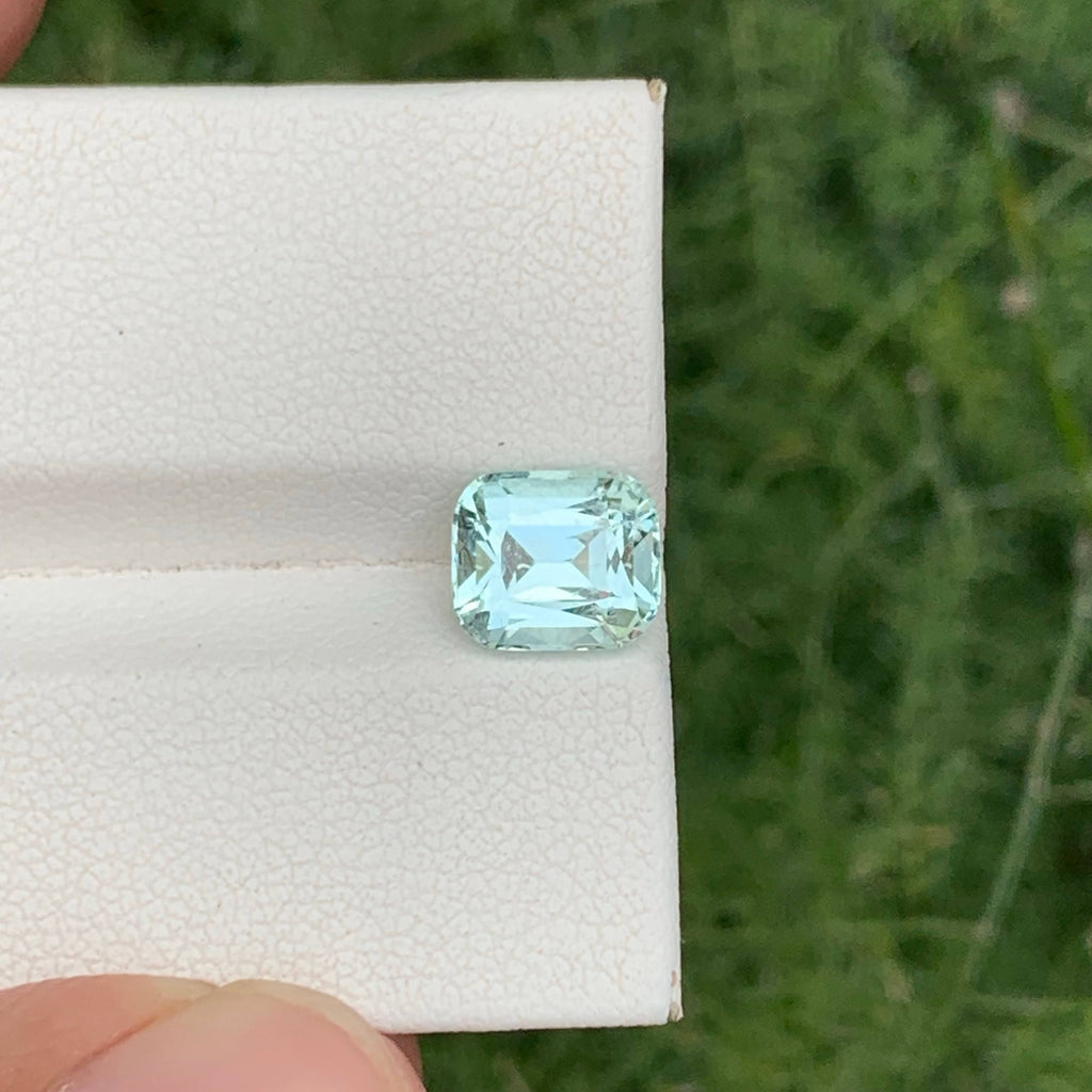 Faceted gemstone on a white cloth with a blurred green background