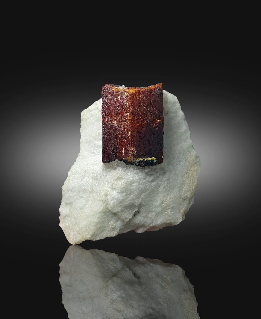 Mineral sample with a brown crystal on a white rock against a dark background