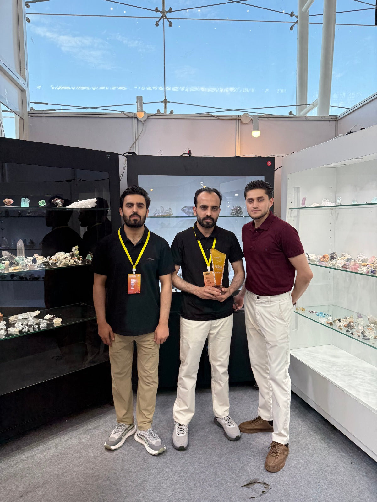 Three men standing in a booth of where minerials has been displayed
