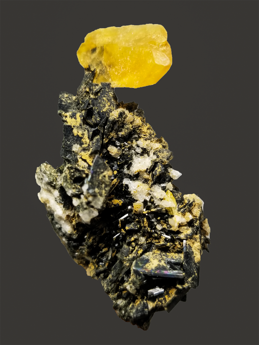 Mineral specimen with a yellow crystal on a dark background