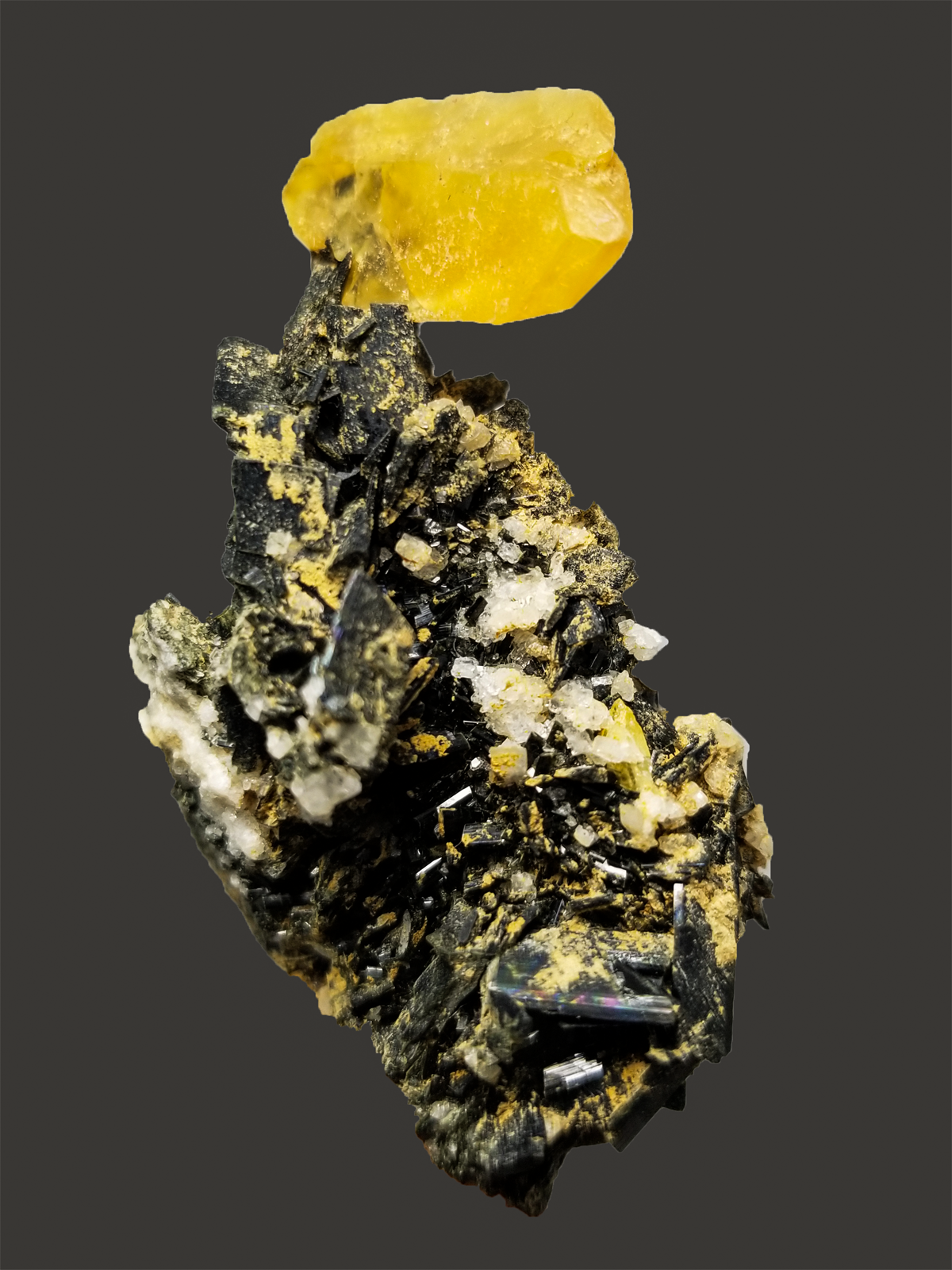 Mineral specimen with a yellow crystal on a dark background