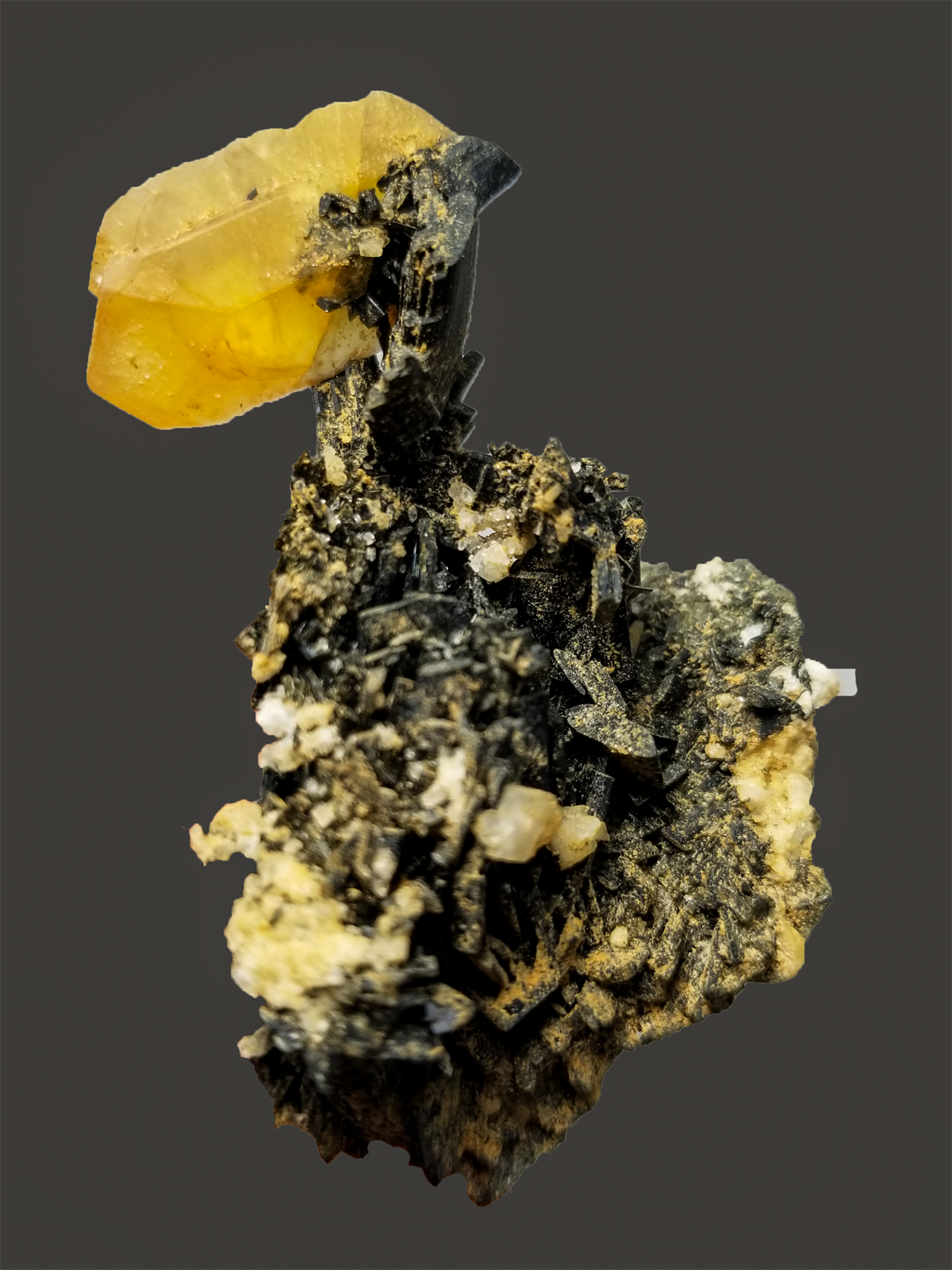 Mineral specimen with a yellow crystal on a dark background